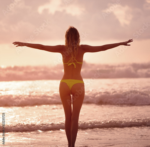 Slender female Silhouette on a background of sea waves and the sky with the setting sun © katafree