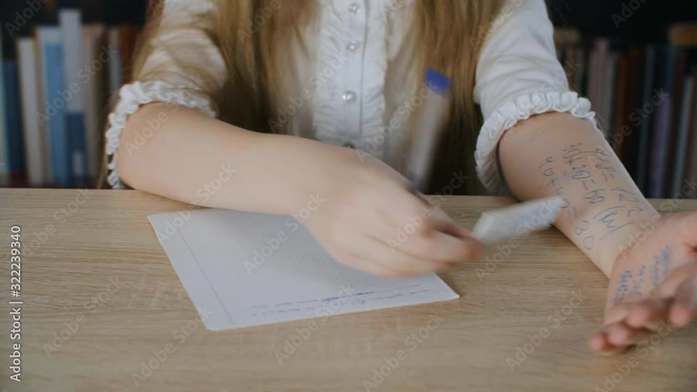 Schoolgirls holding cheat sheet in hand on school exam. Student girl solving task with cheat sheet at school test in class
