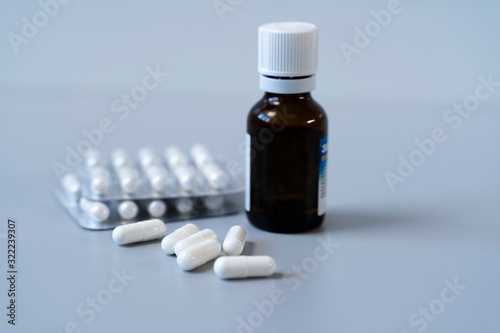 White capsules and vial with injection on a gray background. Pills in blisters.