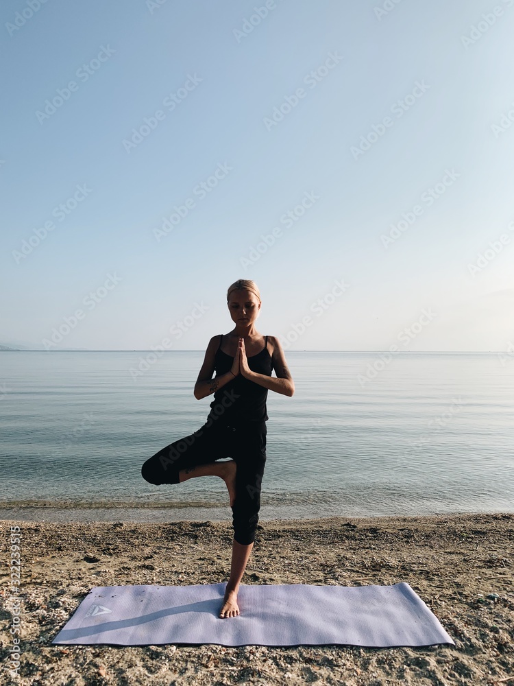 Young blond girl practice yoga on sea shore at sunrise Young blond girl practice yoga on sea shore at sunrise