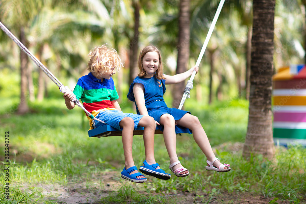 Kids on swing. Playground in tropical resort.
