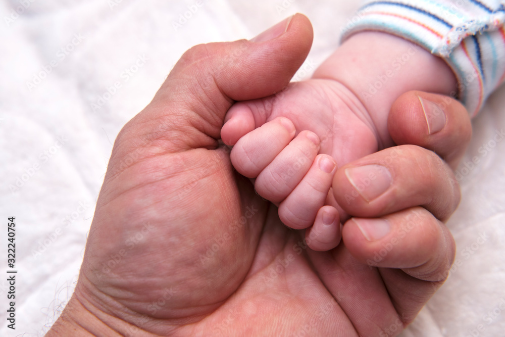 The baby's handle lies in the man's palm.