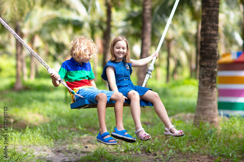 Kids on swing. Playground in tropical resort.