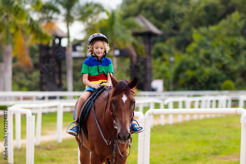 Kids ride horse. Child on pony. Horseback riding.