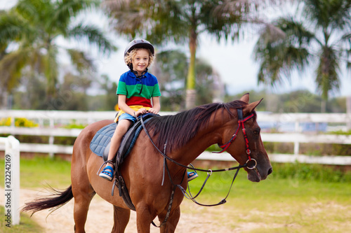 Kids ride horse. Child on pony. Horseback riding. © famveldman