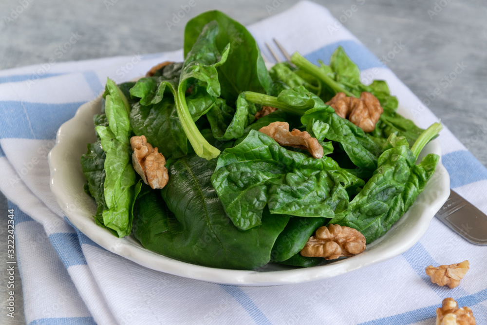Close up view of raw spinach salad with walnuts Close up view of raw spinach salad with walnuts