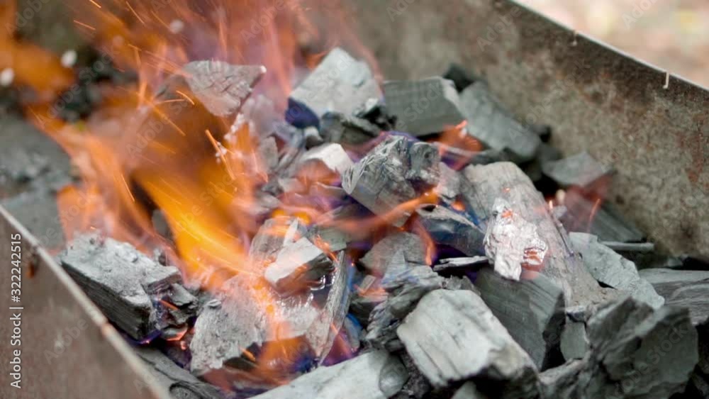 Close-up of burning coals in the barbecue grill. Coal is starting to burn. Hot coal and flame with smoke Close-up of burning coals in the barbecue grill. Coal is starting to burn. Hot coal and flame with smoke