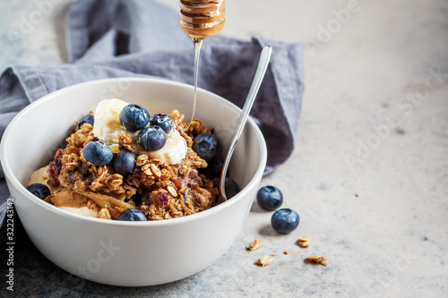 Fotografía Homemade granola bowl with blueberries, banana and honey.
