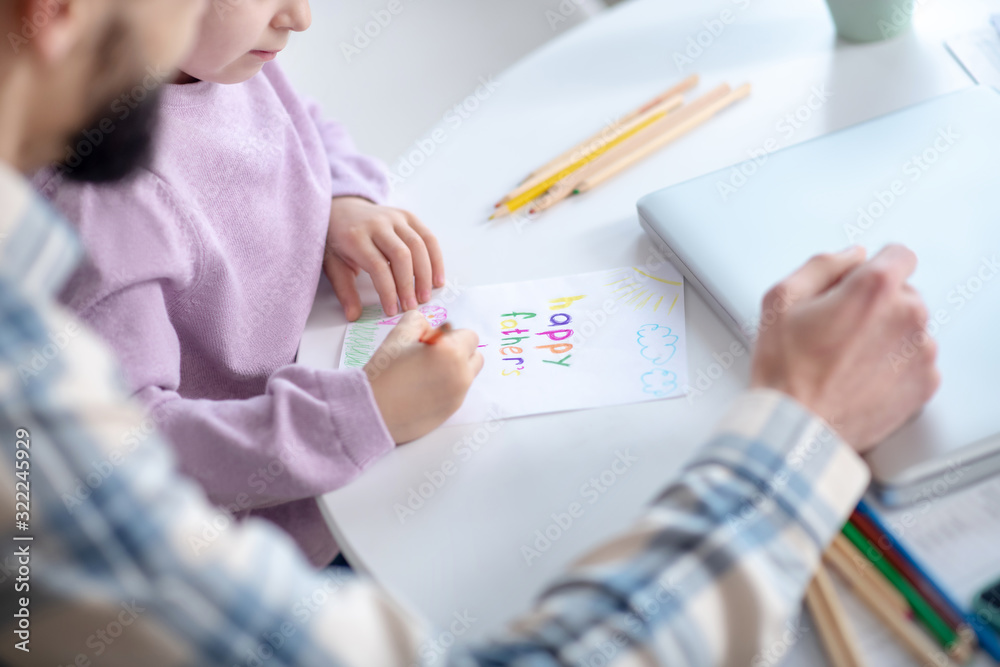 Little girl painting with dad at home.