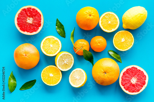 Fresh citrus background. Oranges  grapefruits  leaves - whole fruits and halfs - on blue background top-down