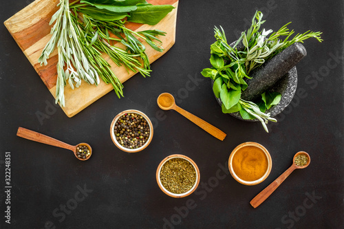 Herbs and spices on black kitchen desk top-down