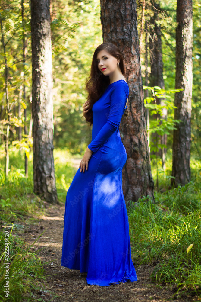 Beautiful, young girl dressed in a blue dress, on a background of a pine forest. Beautiful, young girl dressed in a blue dress, on a background of a pine forest.