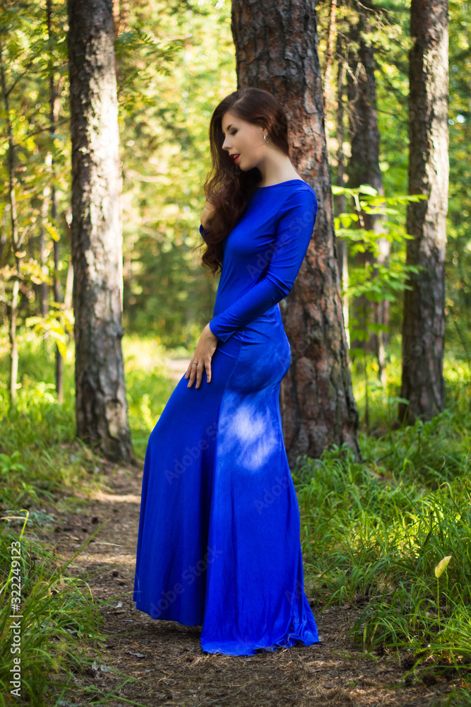 Beautiful, young girl dressed in a blue dress, on a background of a pine forest. Beautiful, young girl dressed in a blue dress, on a background of a pine forest.