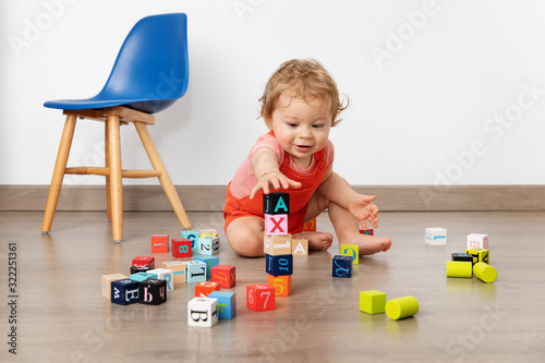Cute baby piling up blocks in playroom