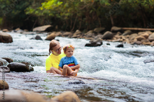 Mother and child swimming in mountain river.