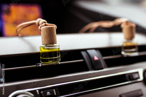 Car air perfume freshener bottles inside the car on car panel. Aromatic liquid in the small bottle.