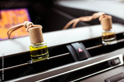 Car air perfume freshener bottles inside the car on car panel. Aromatic liquid in the small bottle.
