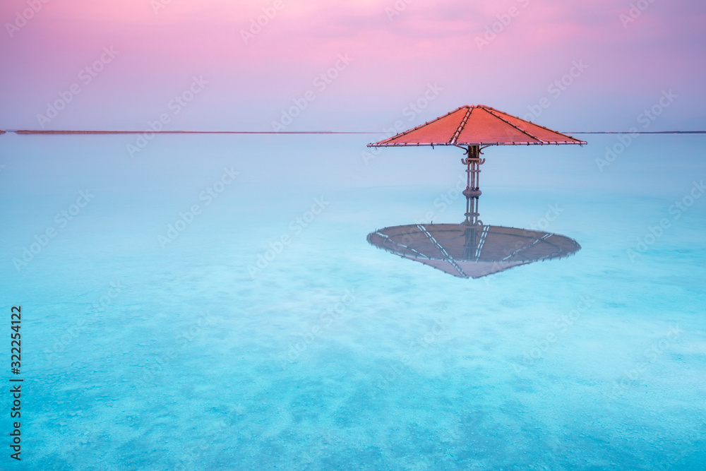 Dead Sea beach. Sun umbrella in water. Minimalist landscape