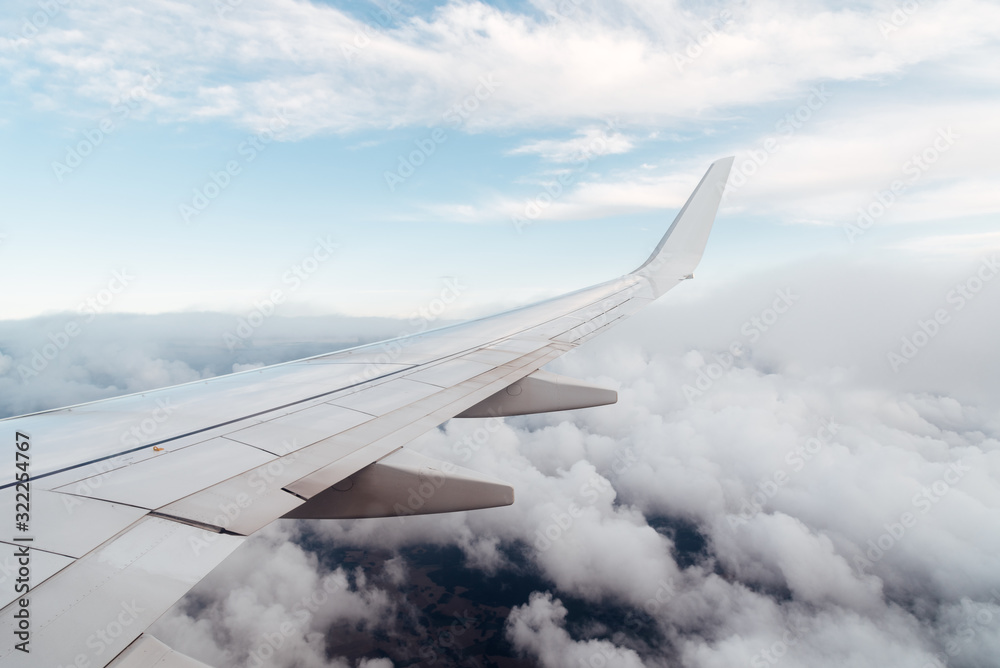 Wing of a flying airplane on clouds, view from the airplane window Wing of a flying airplane on clouds, view from the airplane window