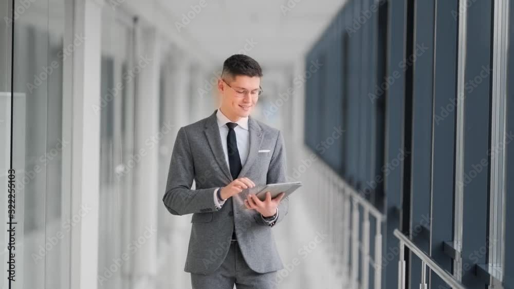 young man in a business suit in the hall of a business center dancer goes with a tablet