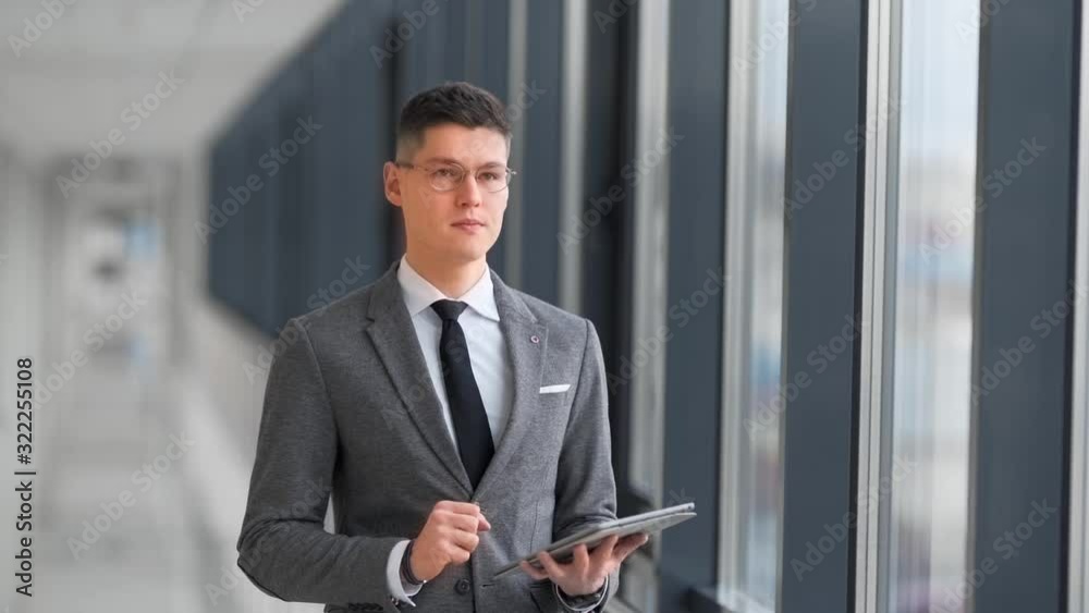 man in business suit in business center hallway with tablet man in business suit in business center hallway with tablet