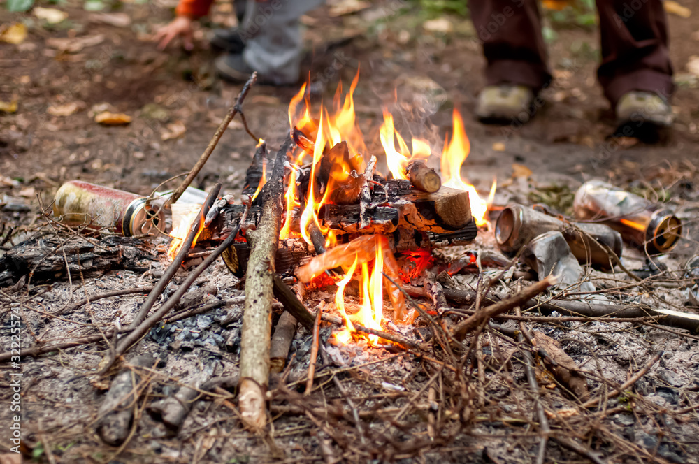 People burning beer cans in the campfire to clean the camping spot People burning beer cans in the campfire to clean the camping spot