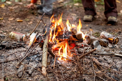 People burning beer cans in the campfire to clean the camping spot