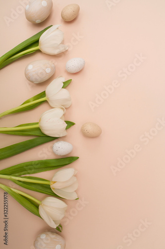 Creative layout With white tulips flowers and Easter eggs on beige background. holiday concept. Flat lay, top view. 