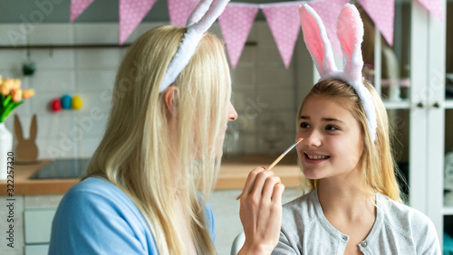 Mother and daughter with bunny ears headbands and painted Easter eggs at home