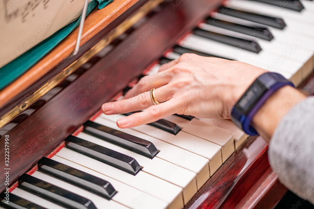 Fototapeta premium Human hand playing the piano with selective focus on finger tips