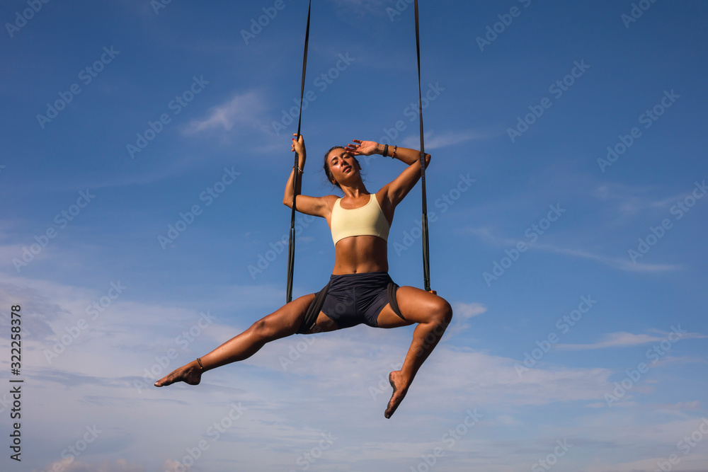 aerial yoga beach workout - young attractive and healthy woman practicing aero-yoga training balance body and mind control hanging from ropes above the sea aerial yoga beach workout - young attractive and healthy woman practicing aero-yoga training balance body and mind control hanging from ropes above the sea
