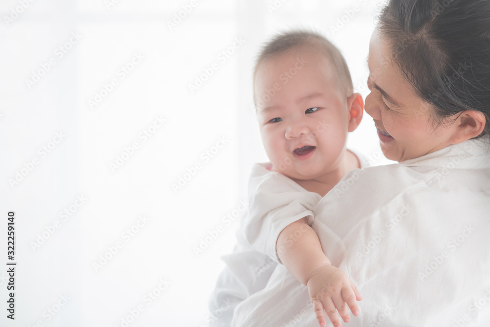 happy loving family. mother playing with her baby in the bedroom. asian mother hugging and holding her baby. family, motherhood, parenting, family and child care concept. White background. happy loving family. mother playing with her baby in the bedroom. asian mother hugging and holding her baby. family, motherhood, parenting, family and child care concept. White background.