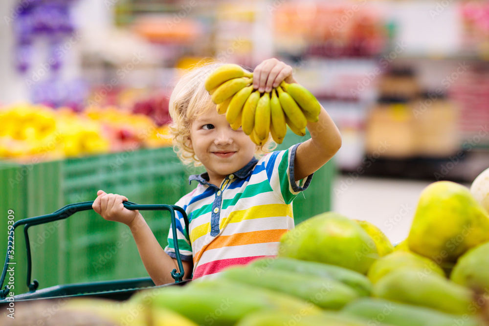 Fototapeta premium Child in supermarket. Kid grocery shopping.