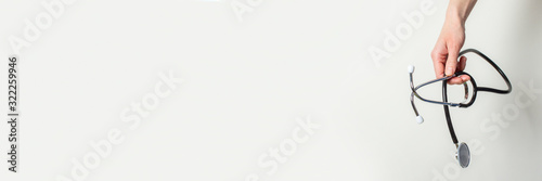 female hand holds a stethoscope on a white background. Banner photo