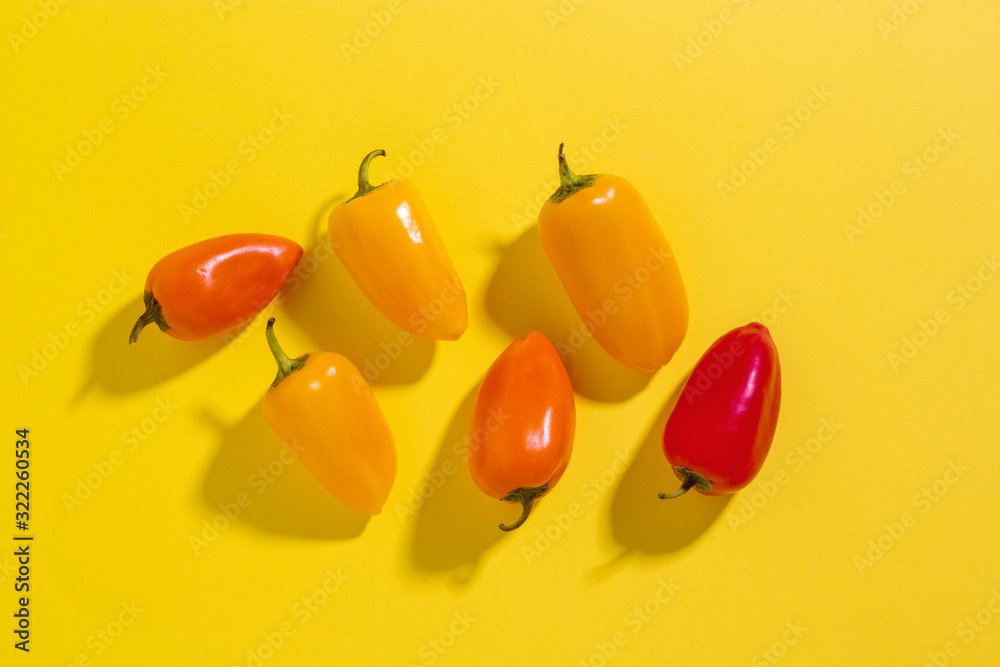 Fototapeta Сolorful yellow, red and orange mini bell peppers on a yellow background with copy space. Vegetables