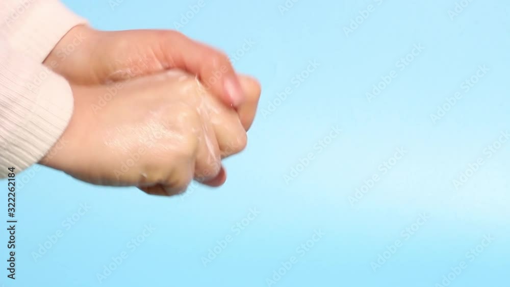 Girl washes her hands with soap close-up on a blue background. Girl washes her hands with soap close-up on a blue background.