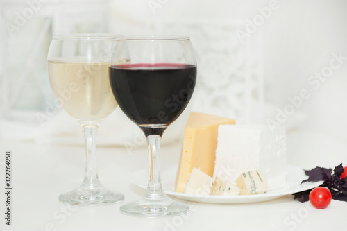 Glasses with red and white wine and cheese on a plate