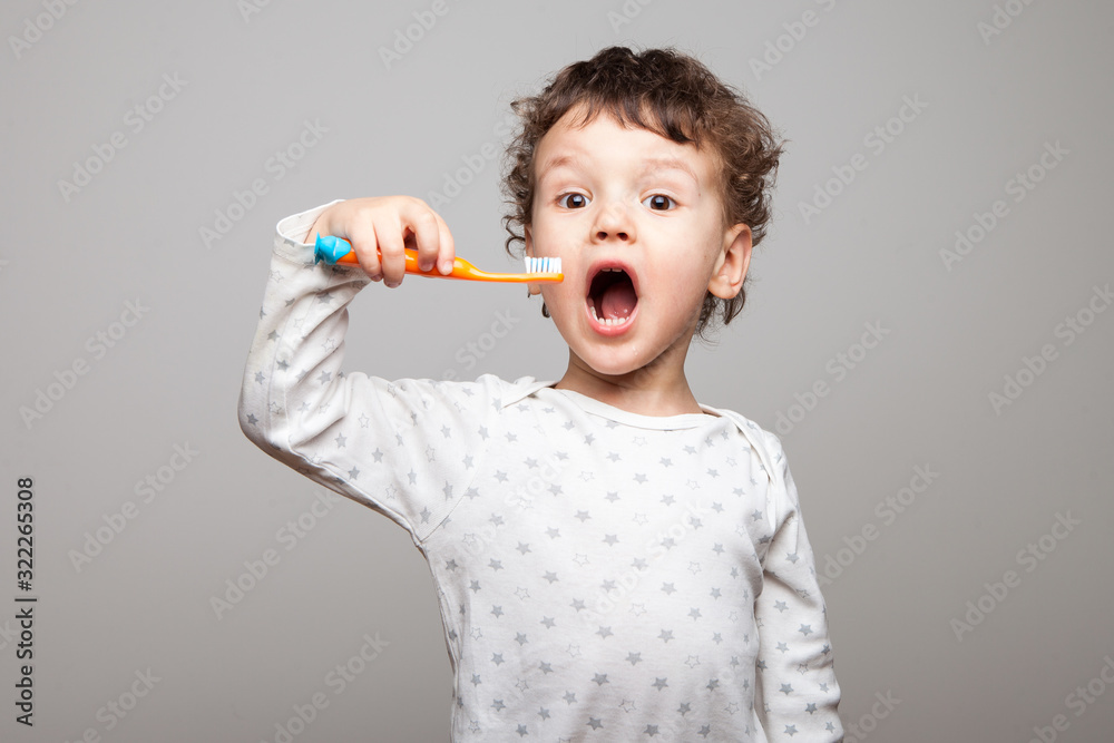 a little boy, a kid with a toothbrush in his hands looks at the counter, is surprised. Enthusiastic look. Hygienic procedures. isolated white background a little boy, a kid with a toothbrush in his hands looks at the counter, is surprised. Enthusiastic look. Hygienic procedures. isolated white background