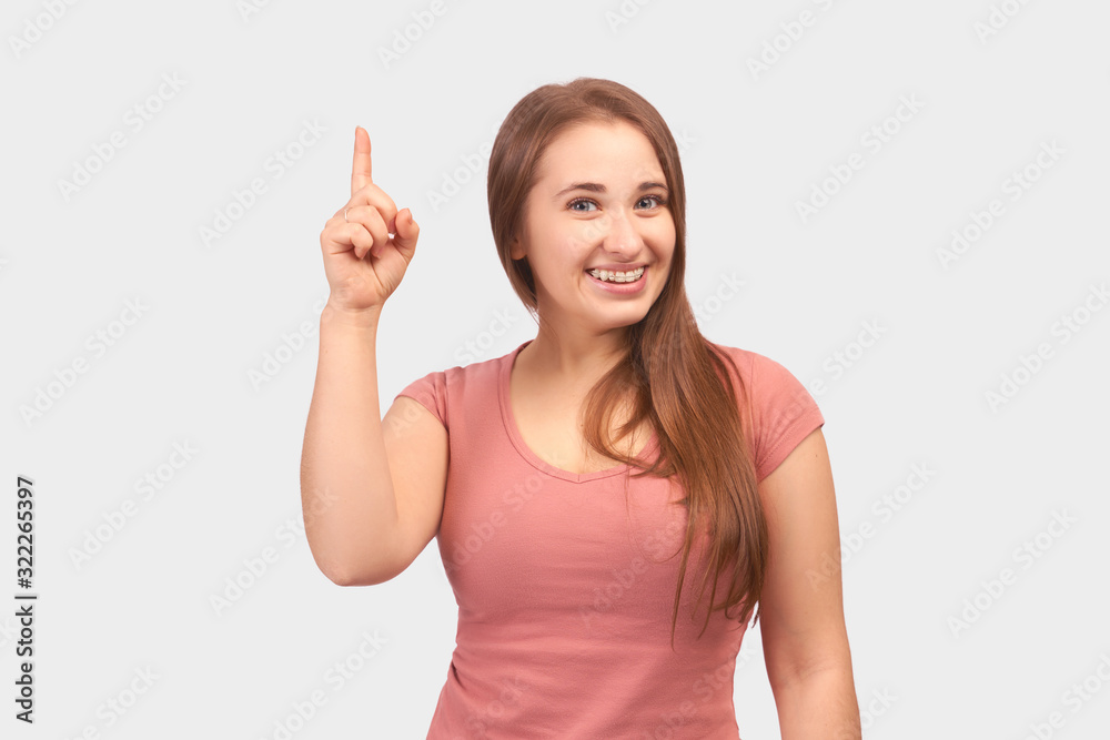 Cute girl smiles widely and points her index finger up. She had a great idea and inspiration. Studio portrait on white background with free space for inserting ads and text. Cute girl smiles widely and points her index finger up. She had a great idea and inspiration. Studio portrait on white background with free space for inserting ads and text.
