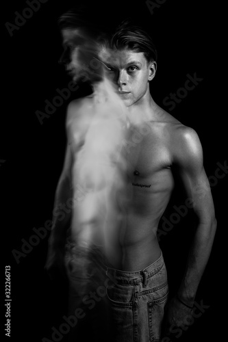 Artistic long exposure moody portrait of young sexy naked torso man. Black and white monochrome creative inspiration. Black background. Confused angry disappointed defending look
