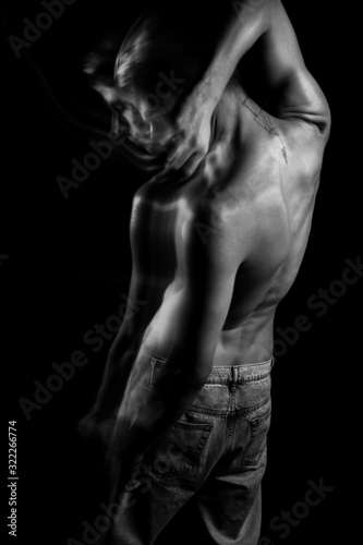 Naked back in black and white. Handsome young man standing on black background. Emotional portraits. negation. Symbolic metaphorical images