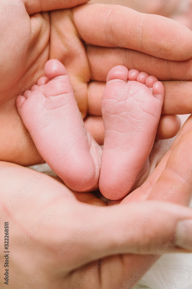 Feet of a newborn baby in the hands of parents. Happy family moment and concept. Feet of a newborn baby in the hands of parents. Happy family moment and concept.