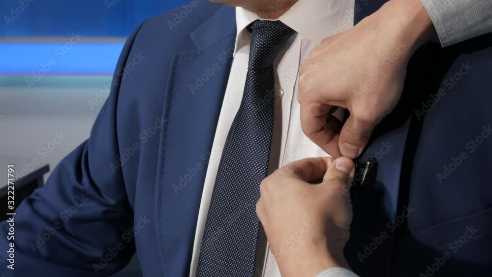 A TV presenter is dressed in a microphone in front of a live broadcast. News.