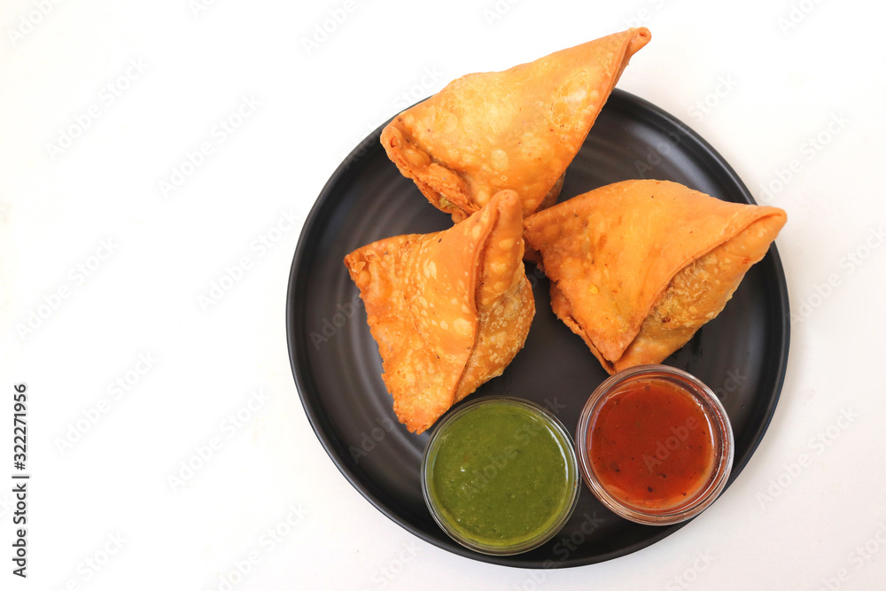 Vegetarian Aloo samosa or samosas. Indian special traditional street food.  Famous Indian Punjabi samosa filled with spicy boiled potato mixture.  served with green and red chutneys. Copy space. Stock Photo