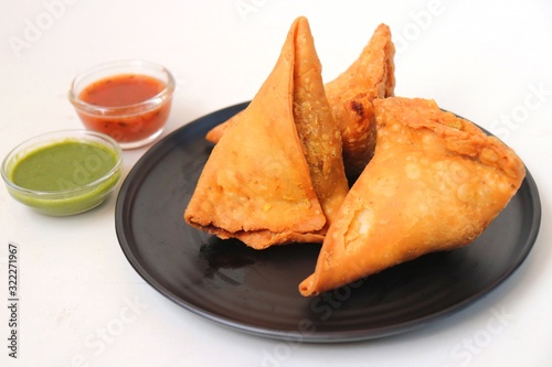 Vegetarian Aloo samosa or samosas. Indian special traditional street food. Famous Indian Punjabi samosa filled with spicy boiled potato mixture. served with green and red chutneys. Copy space.