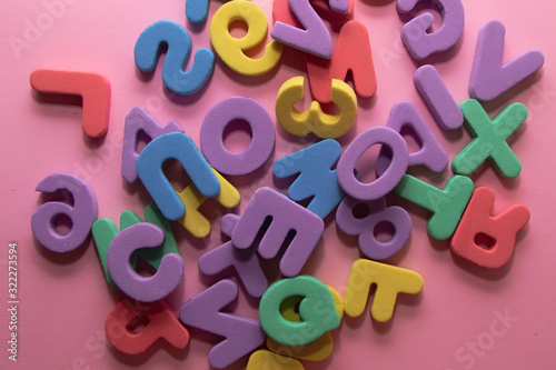 Colorful plastic alphabet letters on pink background, top view