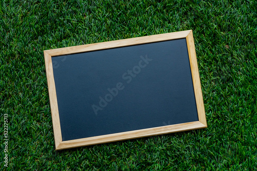 A small blackboard placed on an artificial grass Background for educational illustration.