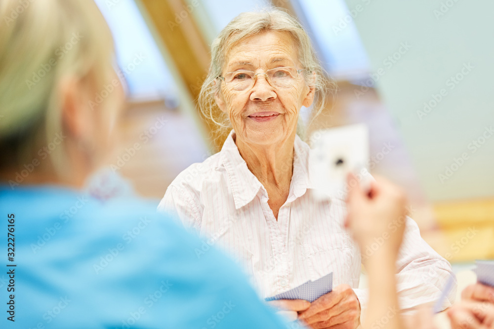 Obraz premium Old woman in card game with caregiver