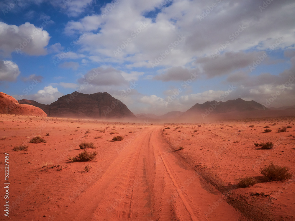 Naklejka premium Beautiful Scenery Scenic Panoramic View Red Sand Desert and Ancient Sandstone Mountains Landscape in Wadi Rum, Jordan during a Sandstorm