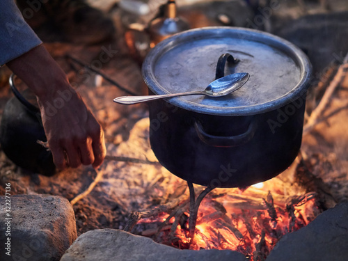 Valokuva Bedouin man cooking traditional bedouin meal on fire in a tent